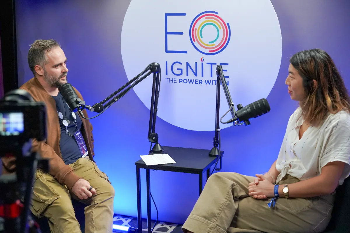 Jon Oliff in conversation with a guest in front of the EO Ignite backdrop