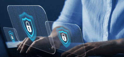 Person typing on a laptop with three transparent digital shield icons displaying padlocks floating above the keyboard against a dark blue background