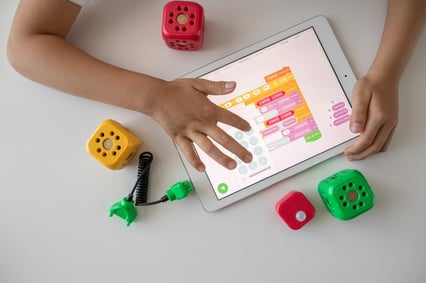 Child interacting with educational coding apps on a tablet with physical blocks