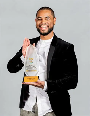 Jamie Thurston Wyngaard smiling while holding a National Presidential Social Enterprise of the Year award.