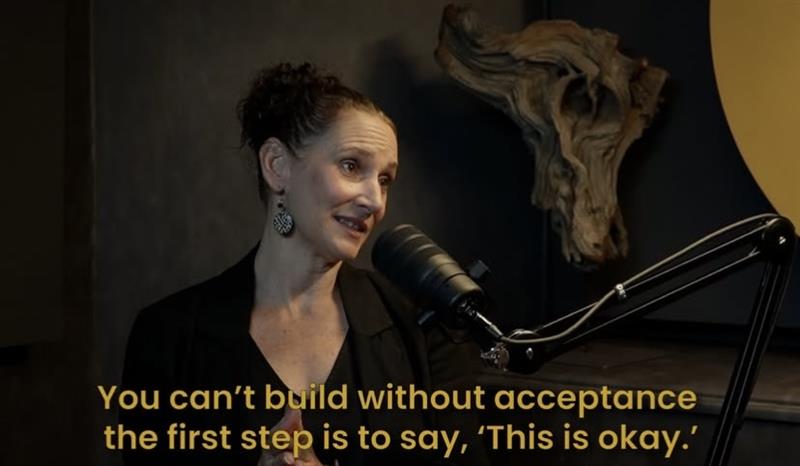 Debra Clelland mid-conversation in the Tim podcast studio, captured as she shares wisdom on acceptance and inclusion in Episode 19. The quote onscreen reads, “You can’t build without acceptance — the first step is to say, ‘This is okay.’” She sits confidently before the mic in a black outfit, framed by the mustard-accented space.
