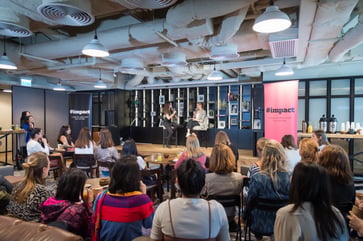Audience watching a panel discussion in an event space.