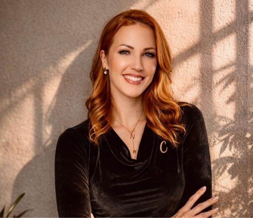 Portrait of Nicole Capper smiling with her arms folded.