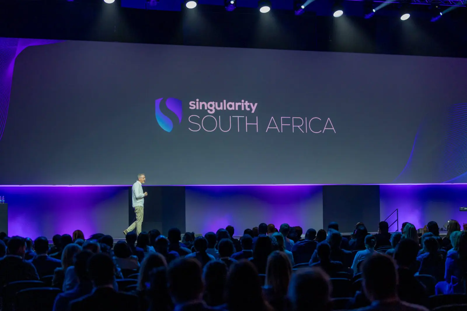 A speaker on stage in front of the Singularity South Africa screen