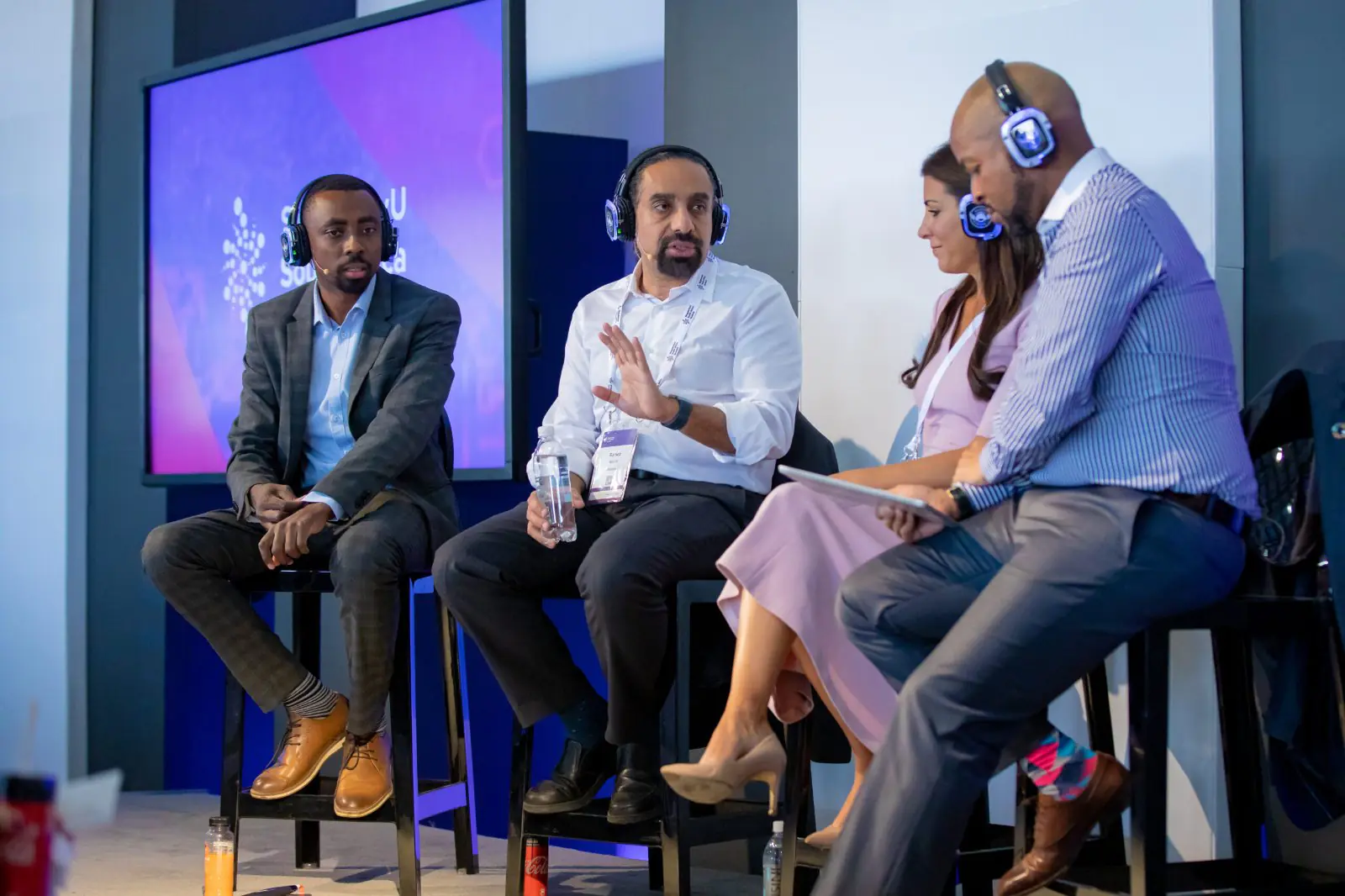 A panel discussion with speakers wearing headphones at the summit