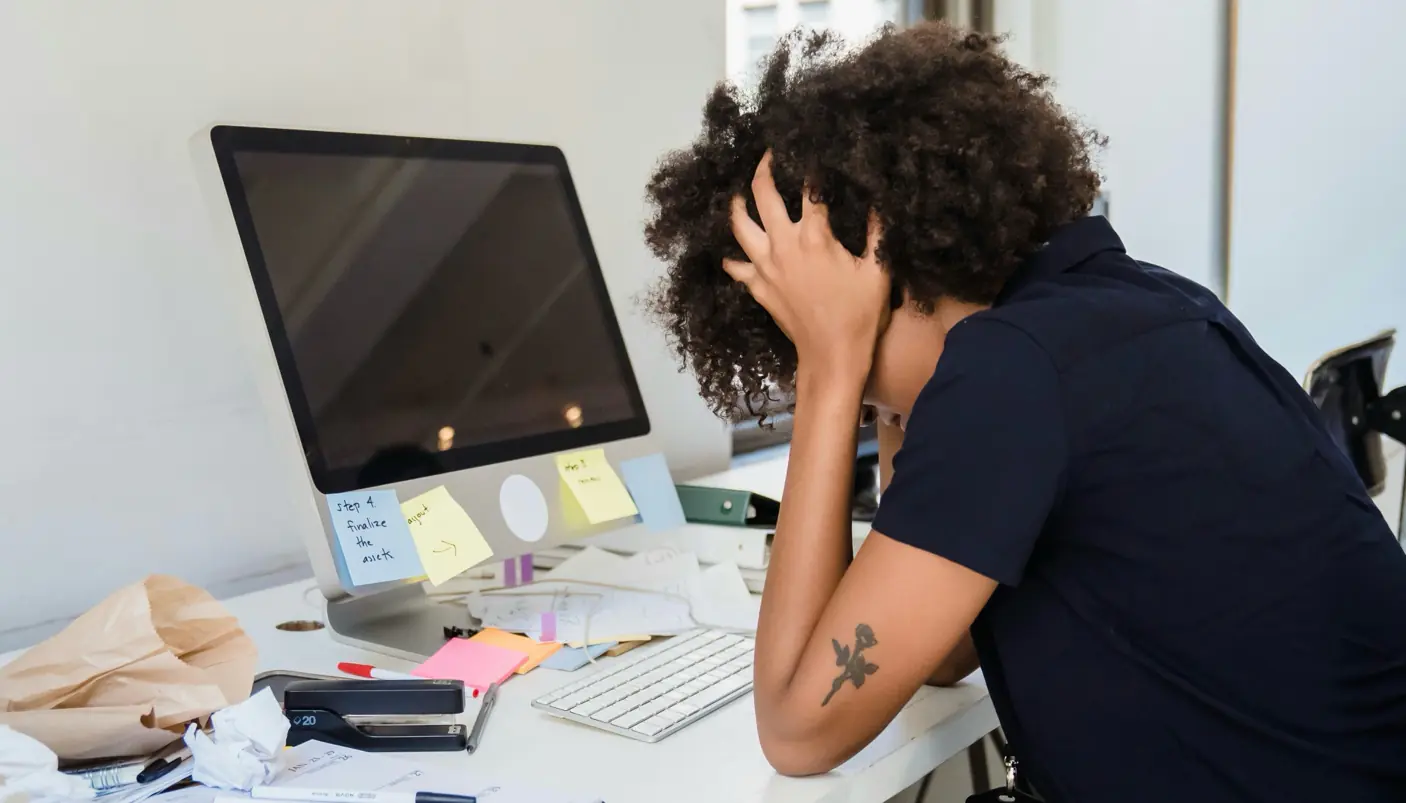A stressed podcast creator at a cluttered desk with their head in their hands