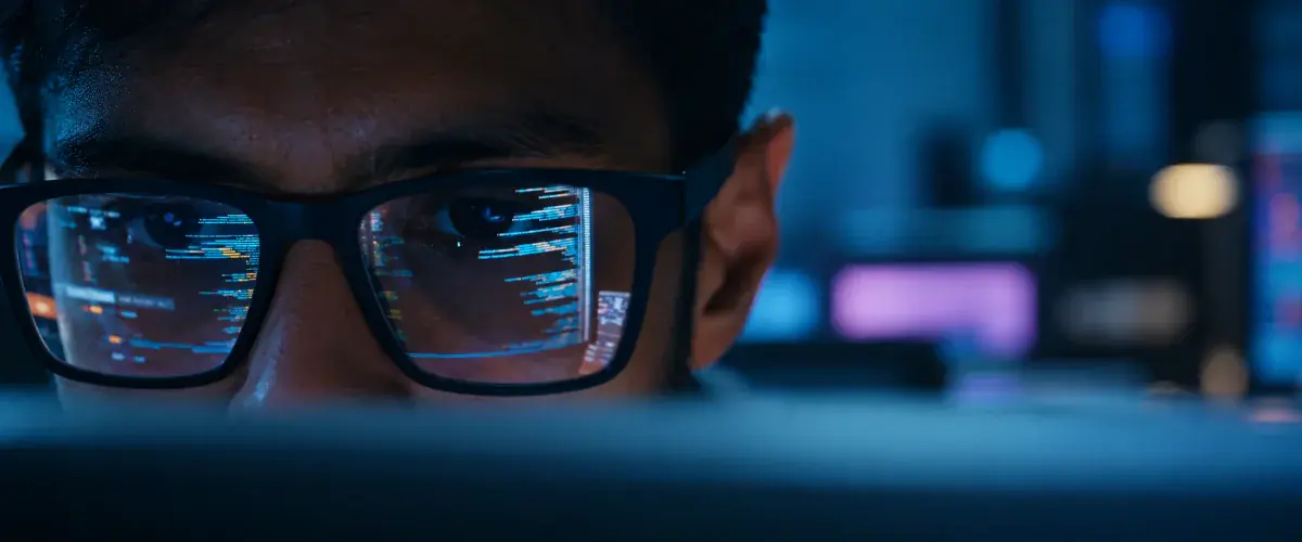 Close-up of a person in glasses with lines of code reflected in the lenses